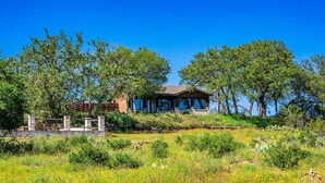 Un rustico chalet con facciata in legno, immerso nel verde e circondato da alberi.