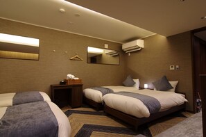 Habitación de hotel con dos camas, una mesita de noche con lámpara, un espejo y un equipo de aire acondicionado.