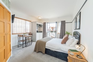 A bedroom with a bed, bedside table, lamp, and a small table with chairs.