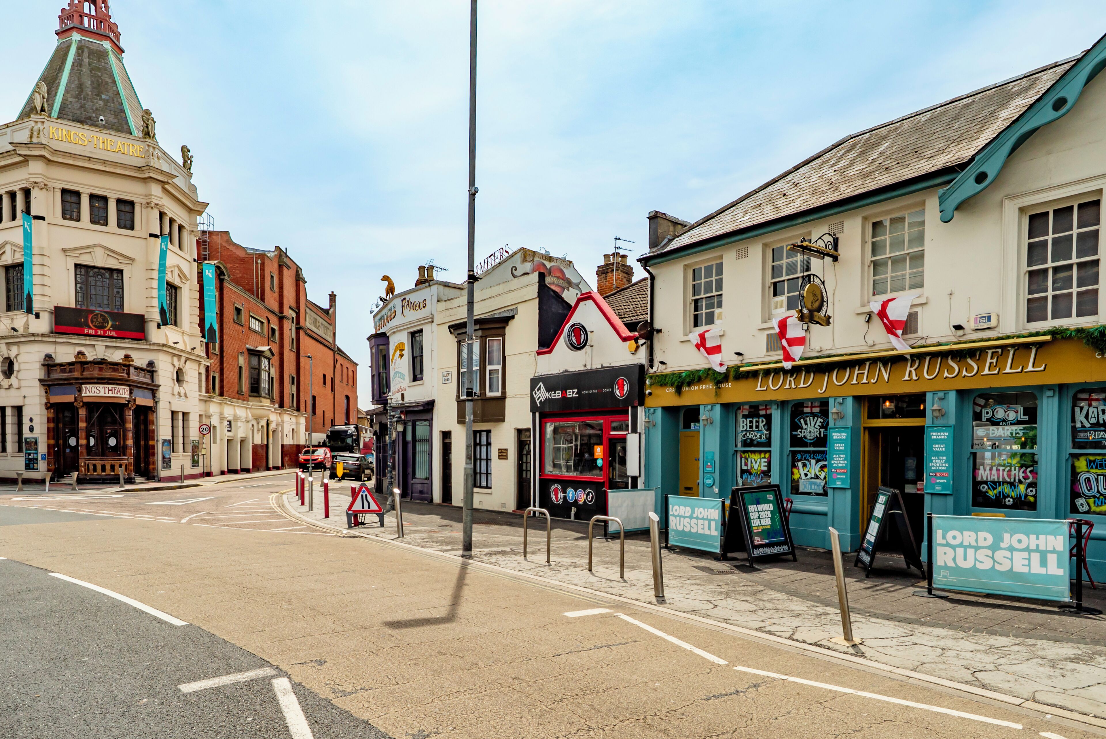 A street with buildings including a theater, a pub, and a restaurant named 'Lord John Russell'.