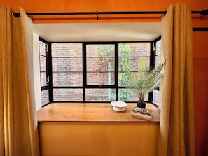 A room with a large window, a wooden table, a potted plant, and a book.