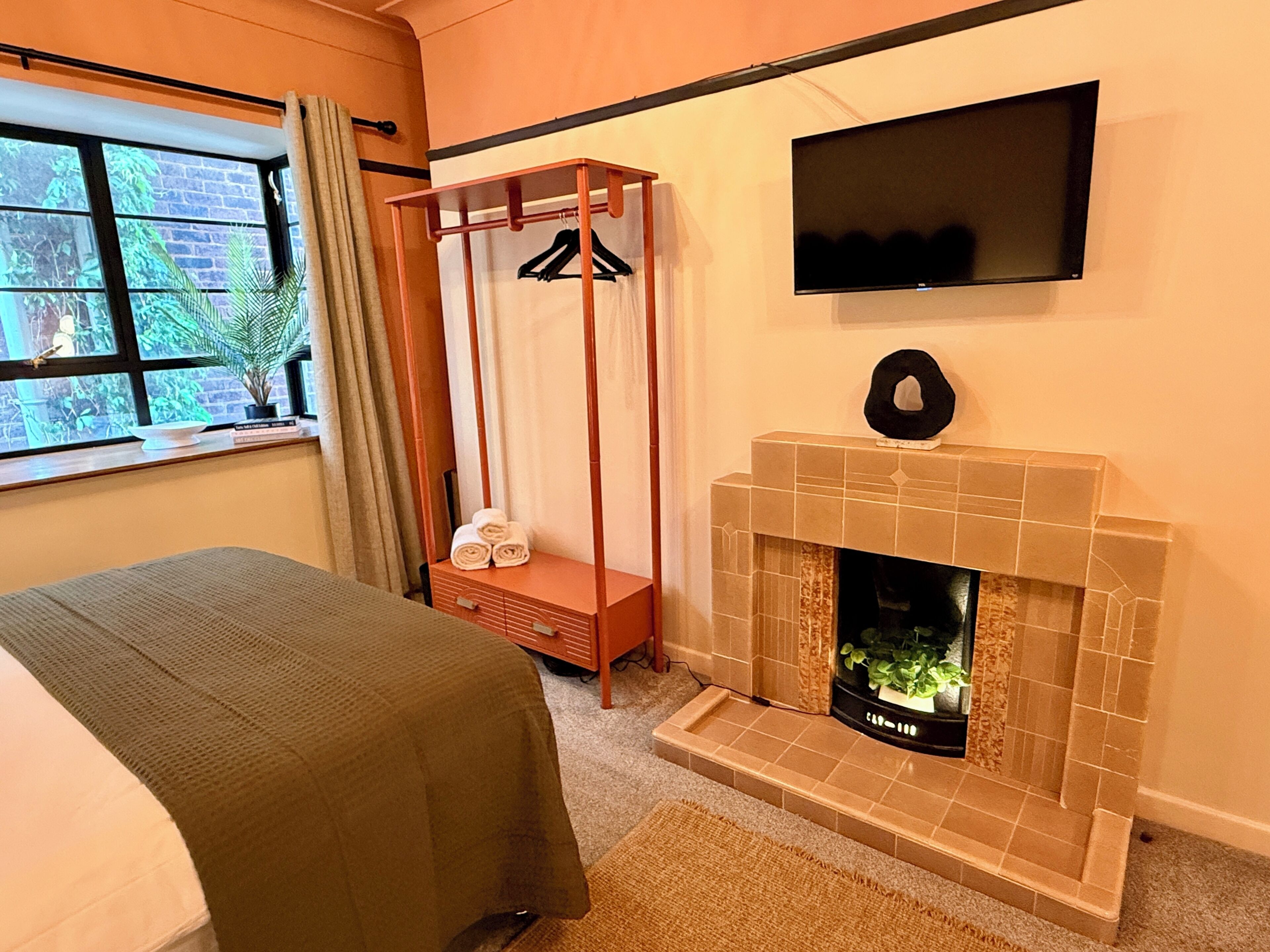Ein Hotelzimmer mit Bett, Nachttisch, Wandfernseher und Kamin.