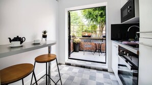A compact kitchen with a dining area, a large window, and a view of a garden.