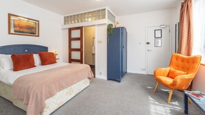 A bedroom with a bed, a chair, a door, and a window.