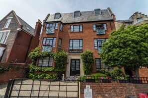 A multi-story brick building with a central entrance, windows with shutters, and a sign above the door. - Art Deco studio with private terrace. Bright, comfortable base near Albert Road's restaurants and a short walk to the seafront. (Portsmouth)