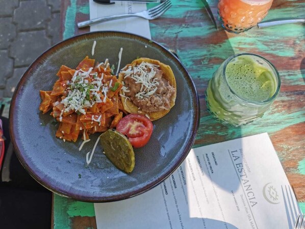 Un plato de comida, un menú y una bebida sobre una mesa.