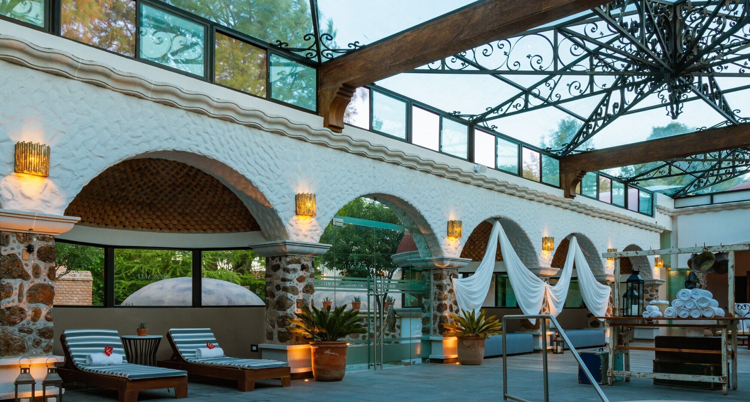 Un'ampia terrazza esterna con archi in pietra, poltrone relax e piante in vaso.
