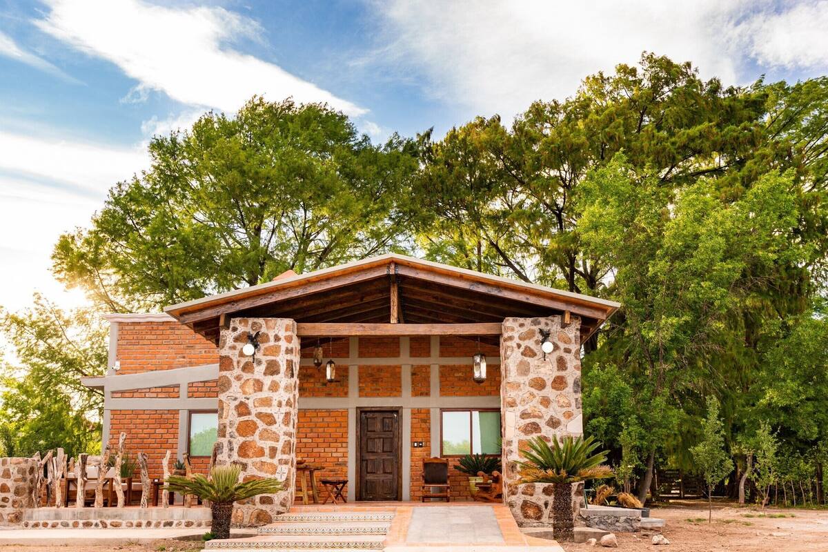 A rustic building with a stone facade, wooden beams, and a brick extension.