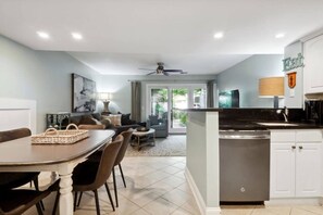A modern kitchen with white cabinets, a black countertop, and a built-in dishwasher.
