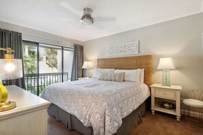 Camera da letto con un letto grande, due comodini, una ventola a soffitto e vista sull'esterno.