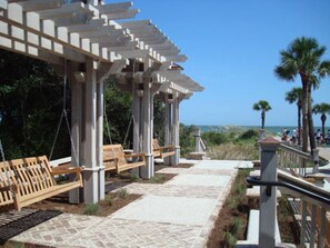 A covered outdoor seating area with benches and a pathway leading to a beach.
