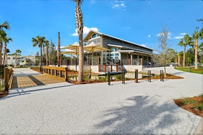 A modern building with a covered walkway, palm trees, and a clear sky. - Stylish Beach Retreat Walk to the Sand from Beach (Hilton Head Island)