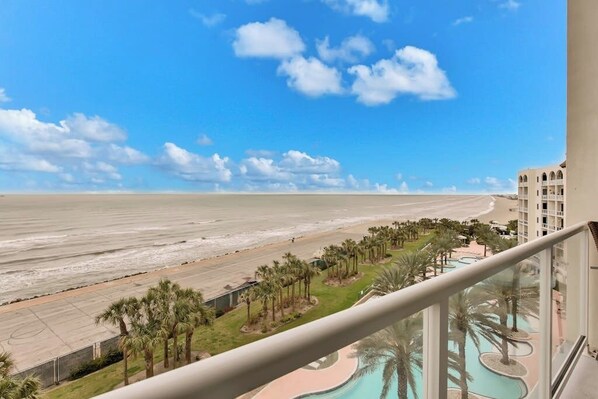 A beachfront hotel with a pool, palm trees, and a clear view of the ocean.