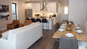 A modern kitchen with white cabinets, a central island, and a dining area with a wooden table set for six. - Stunning Downtown Home on Sherman Avenue (Coeur d'Alene)