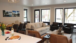 A modern living room with a sofa, armchairs, and a dining area with a table set for two. - Stunning Downtown Home on Sherman Avenue (Coeur d'Alene)