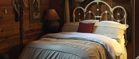 A wooden cabin-style room with a bed, a lamp, and a wall-mounted picture.