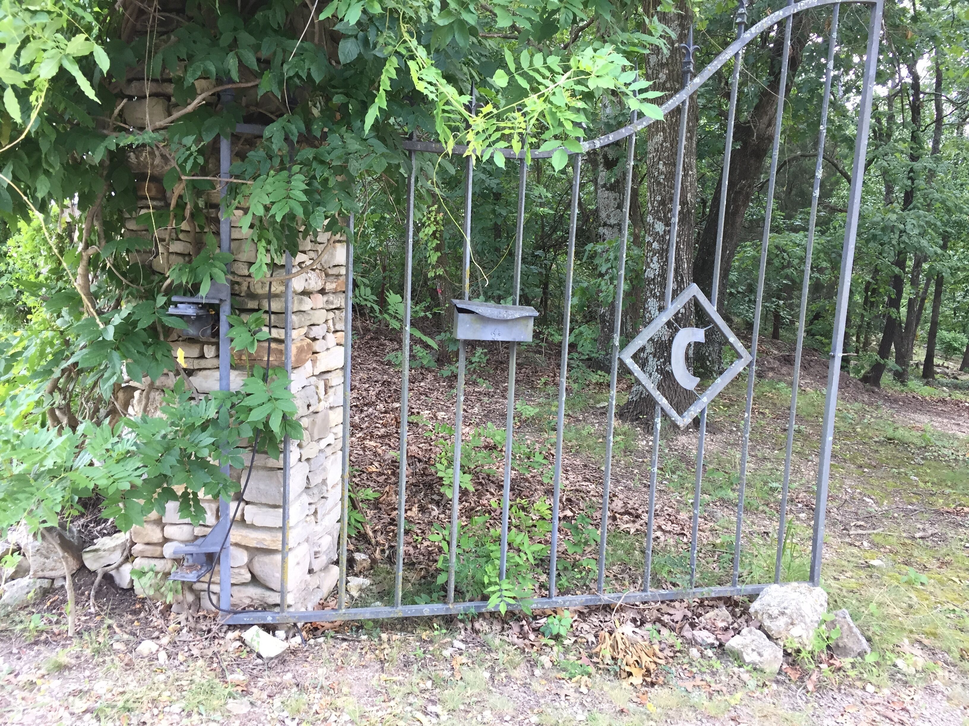 Een metalen poort met een stenen muur en een vogelvoerder.