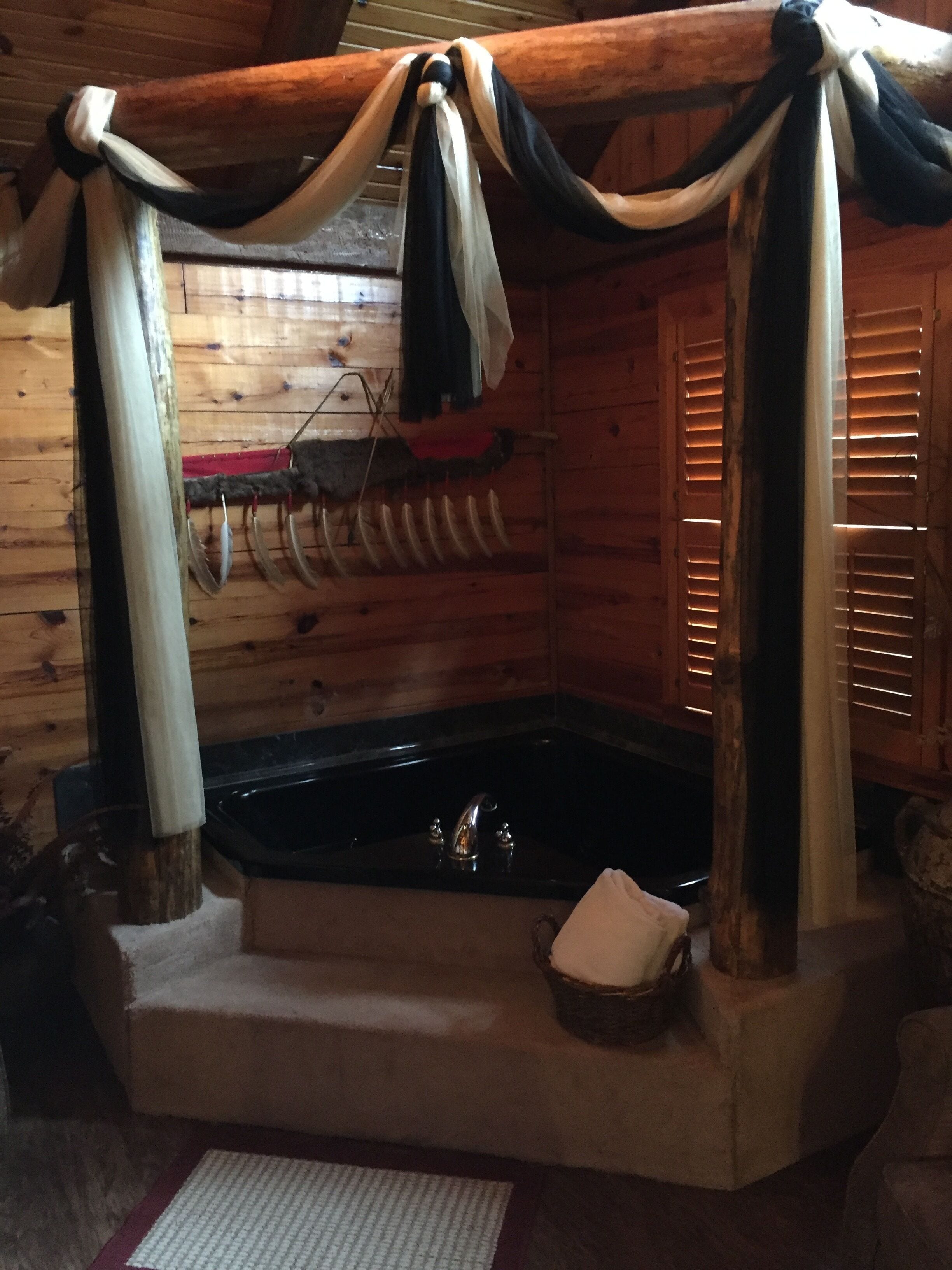 En stuga med träpanel på insidan, utrustad med ett bubbelbad, träväggar och en rustik inredning.