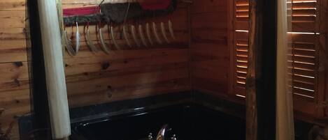 En stuga med träpanel på insidan, utrustad med ett bubbelbad, träväggar och en rustik inredning.