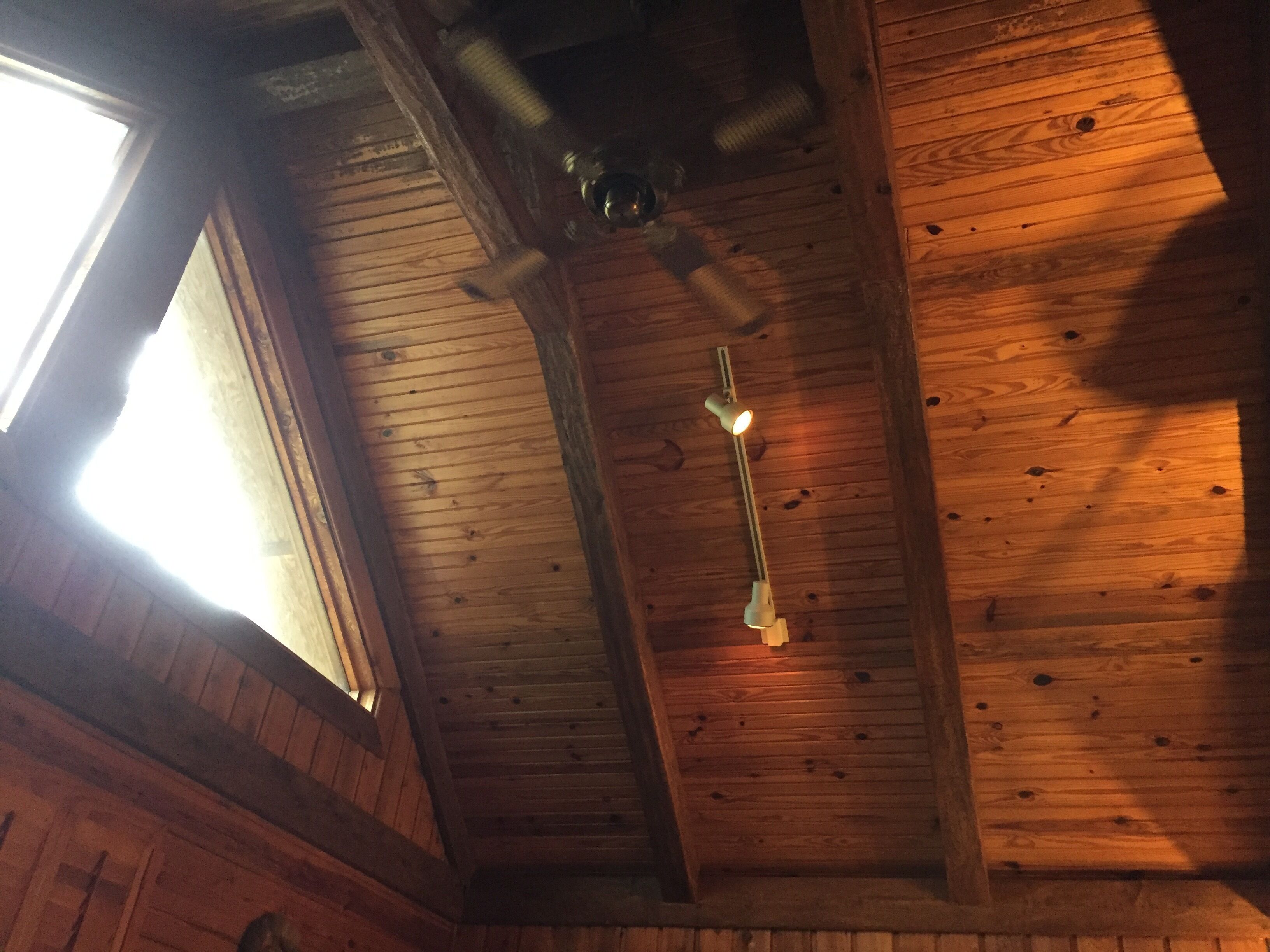 Un soffitto in legno con un lucernario e una lampada a sospensione.