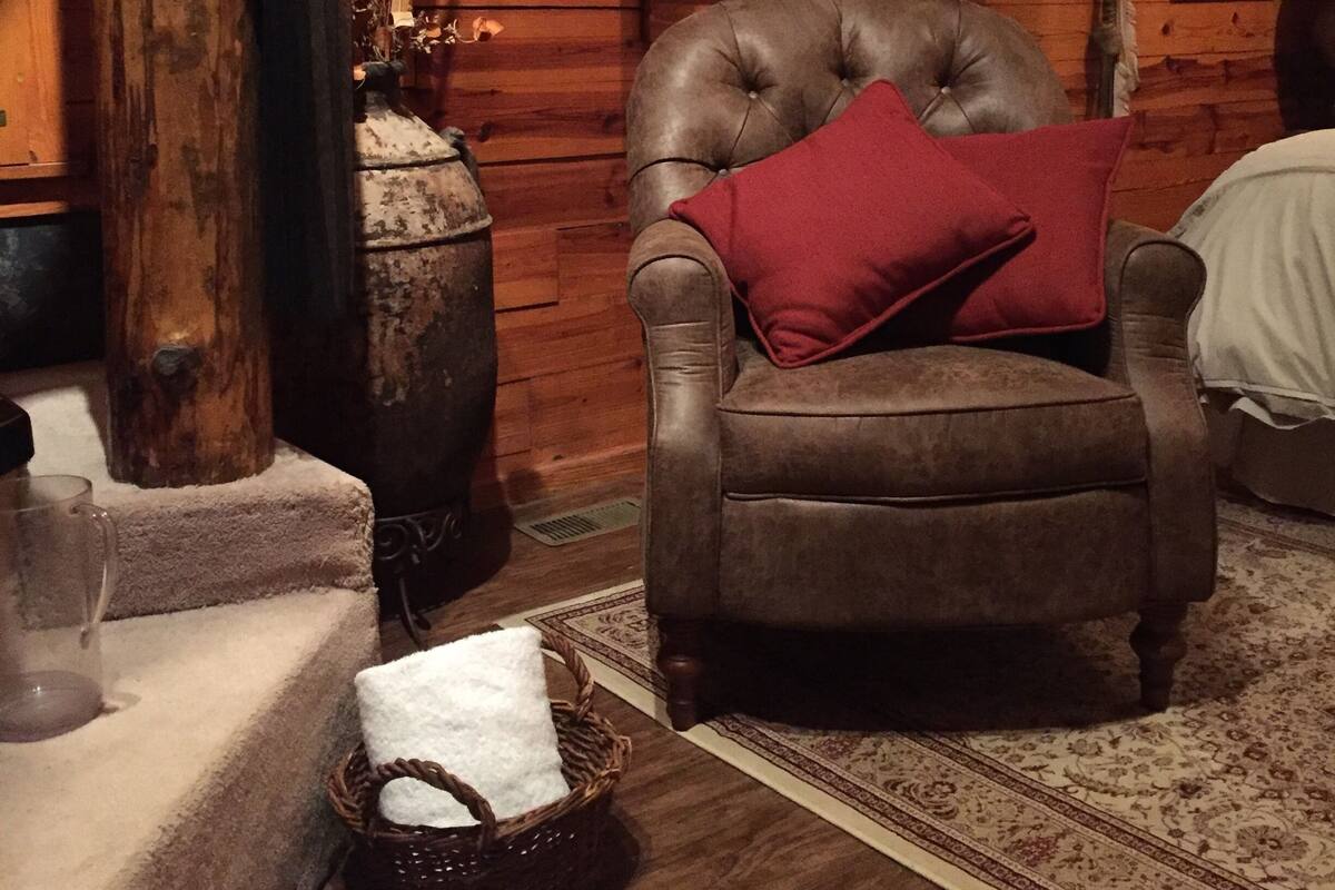 A cozy room with a leather armchair, a vase with dried flowers, and a wooden wall.