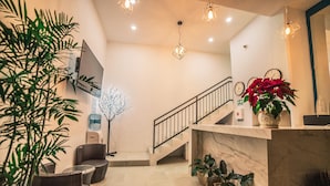 Eine moderne Lobby mit Treppe, Topfpflanzen und einer Rezeption.