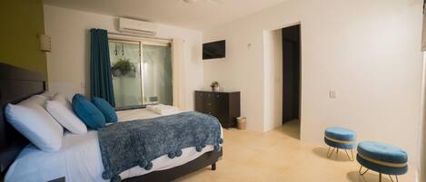 A bedroom with a bed, a ceiling fan, a TV, and a window with curtains.