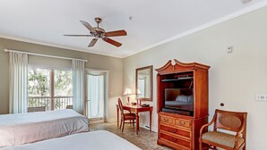 A hotel room with two beds, a desk with a chair, a television, and a wardrobe.