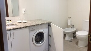 A compact bathroom with a washing machine, a bidet, and a toilet. - Cosy  Apartment at Lido with Pool (Funchal)