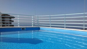 A swimming pool with clear blue water, surrounded by a metal railing. - Cosy  Apartment at Lido with Pool (Funchal)