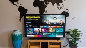 Een flatscreen televisie aan een muur bevestigd, met een wereldkaart sticker, waarop een streamingdienst interface wordt weergegeven.