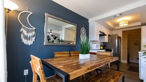 Een moderne keuken met witte kasten, een houten eettafel en een grote spiegel.