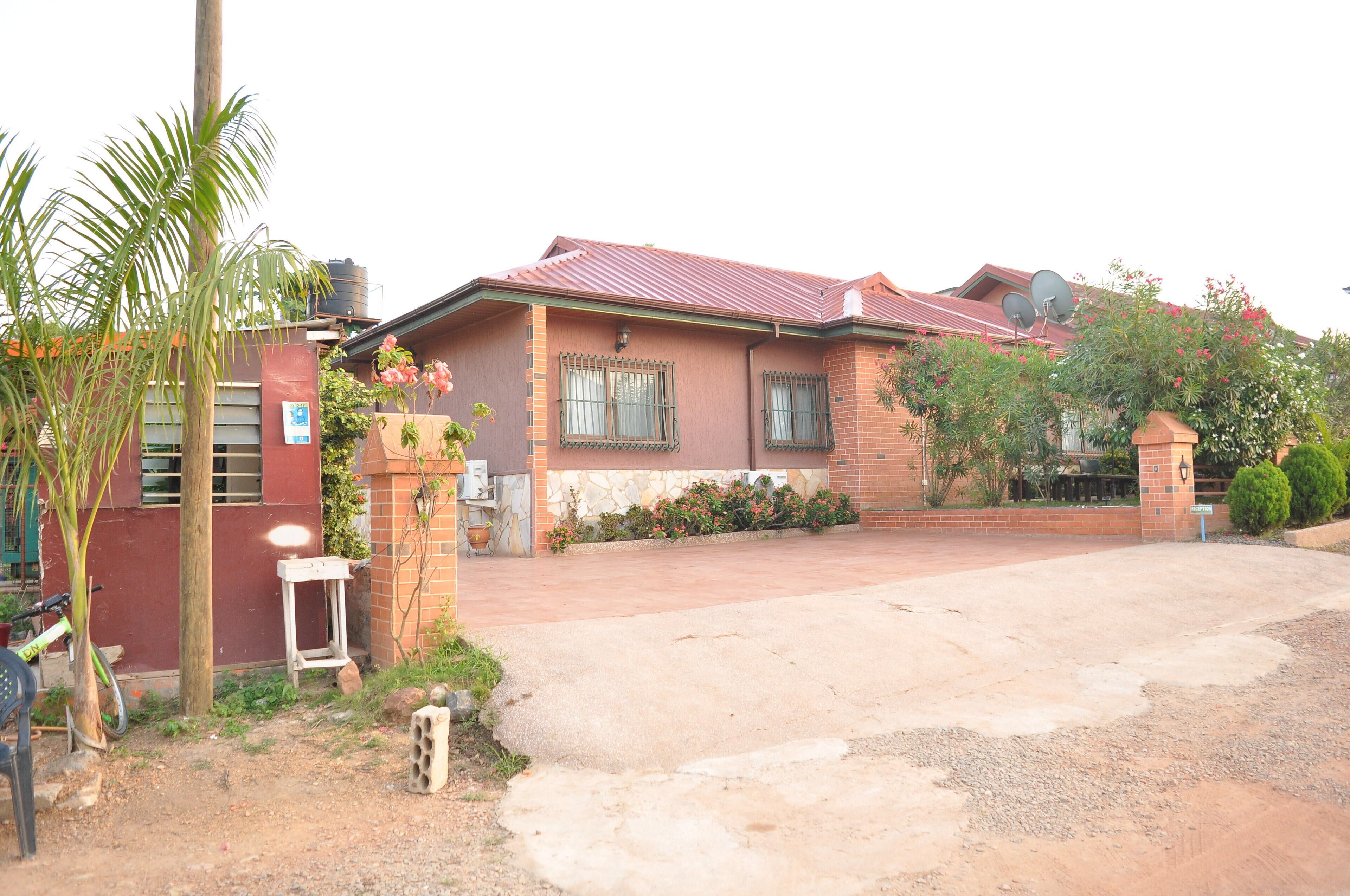 Uma casa de dois andares com telhado vermelho, fachada de tijolos e entrada com calçada.