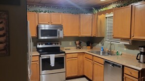 Una cocina con armarios de madera, electrodomésticos de acero inoxidable y suelo de baldosas.