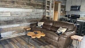 Een gezellige woonkamer met een bruine leren bank, twee houten salontafels en een houten vloer.