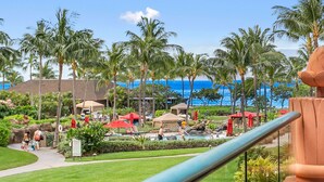 A resort with a pool area, palm trees, and a view of the ocean. - Maui Resort Rentals: Honua Kai Konea 239 - Upgraded Ocean View 2BR, Deluxe Corner Suite (Lahaina)
