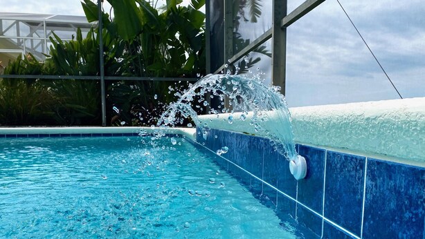 A swimming pool with clear blue water and a water spout. - Overlooking the golf course with spacious interior! (Davenport)