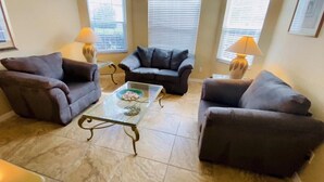 A living room with two sofas, a glass coffee table, and two lamps. - Overlooking the golf course with spacious interior! (Davenport)