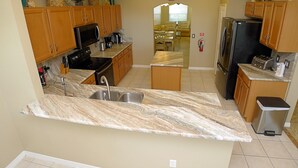 A kitchen with wooden cabinets, a stainless steel sink, a microwave, a refrigerator, and a toaster. - Overlooking the golf course with spacious interior! (Davenport)