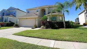A residential house with a garage, a well-maintained lawn, and a clear blue sky. - Overlooking the golf course with spacious interior! (Davenport)