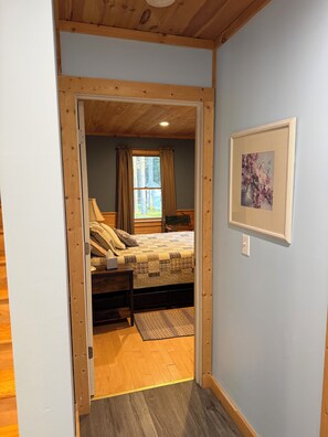 A bedroom with a bed, a nightstand, a framed picture on the wall, and a window with curtains.