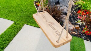 A wooden swing hanging from a tree in a garden with artificial grass and potted plants. - Belmont Shore BH - Unit A  (Long Beach)
