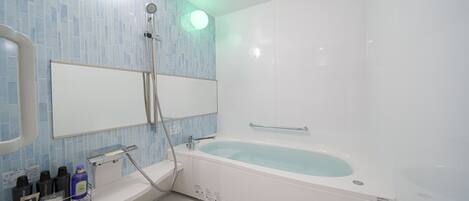 Een moderne badkamer met een ruim bad, een douche en een wastafel met toiletartikelen.