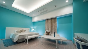 Ein modernes Hotelzimmer mit einem Bett, einem kleinen Esstisch und einer Sitzecke.