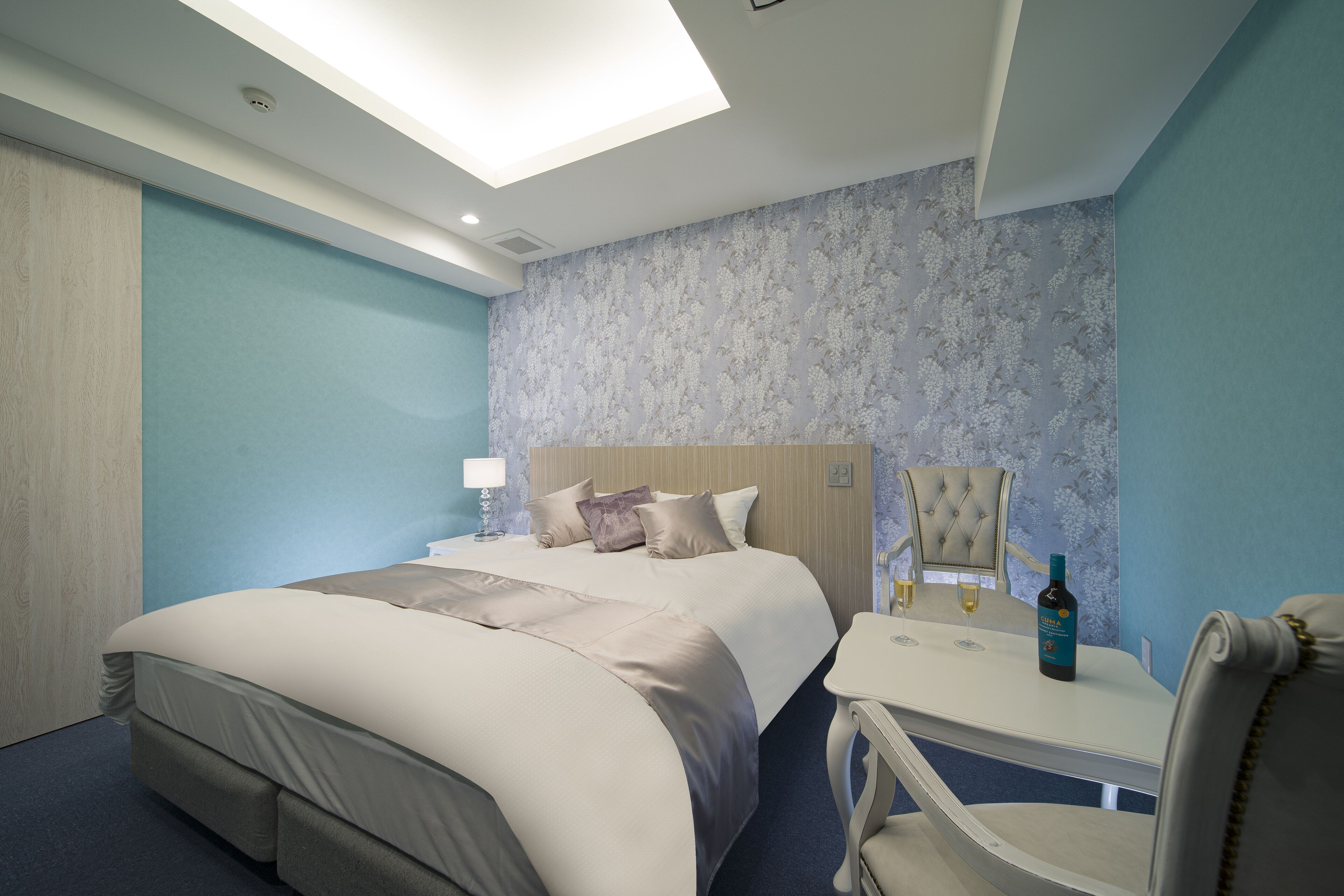 A modern hotel room with a large bed, a desk, and a chair.