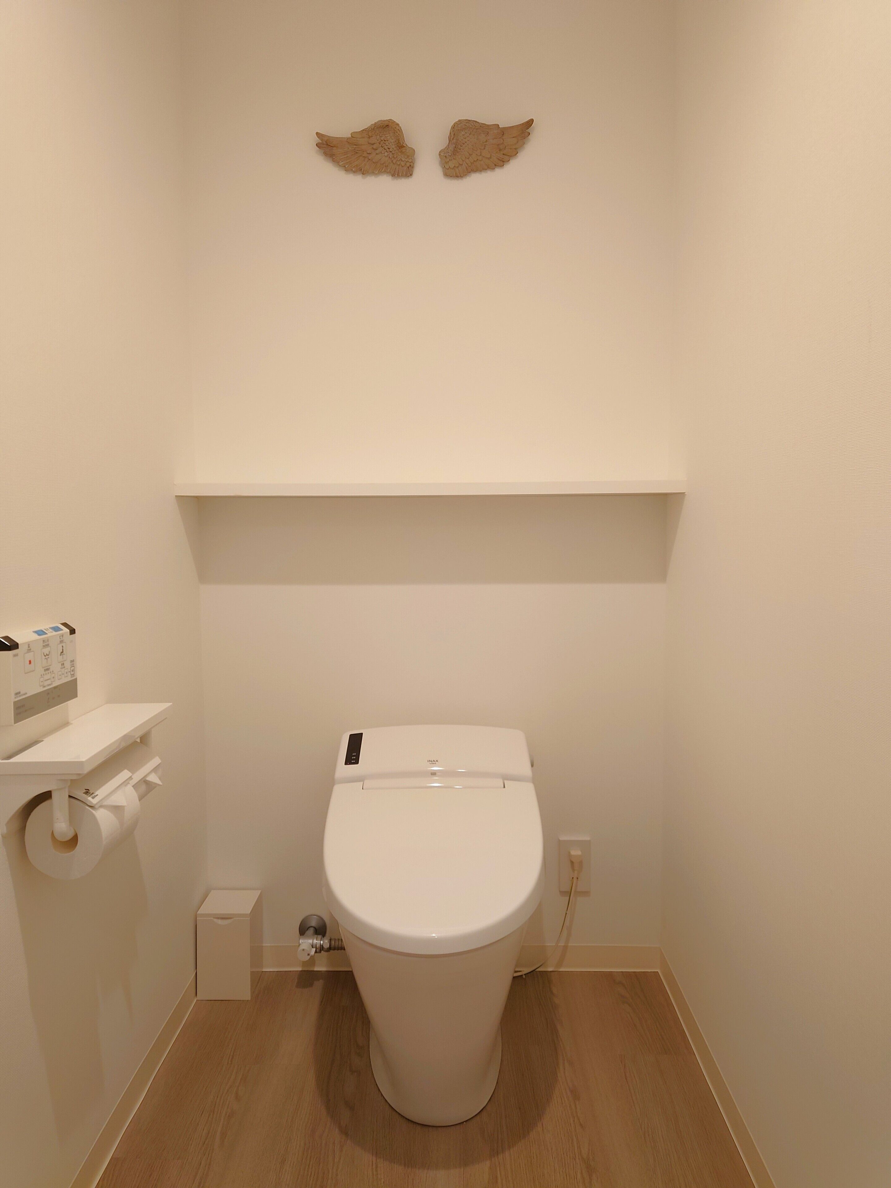 Une petite salle de bain moderne, équipée de toilettes, d’un porte-rouleau de papier toilette et d’une étagère.