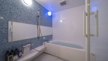 A modern bathroom with a large bathtub, a shower, and a sink.