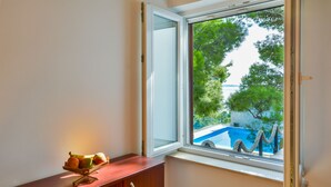 Una habitación con un armario de madera y ventana con vista a una piscina y árboles.