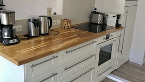 Een moderne keuken met een houten aanrecht, roestvrijstalen apparatuur en witte kastjes.