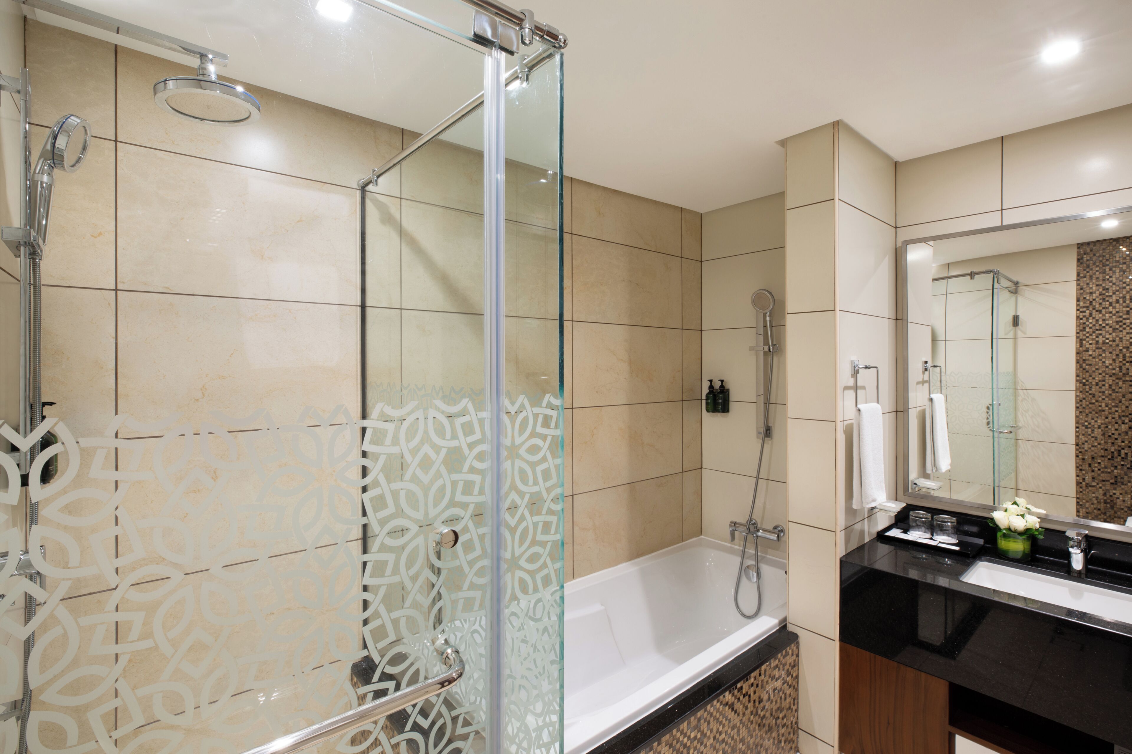 Een moderne badkamer met een douchecabine van glas, een vrijstaand bad en een wastafel met spiegel.